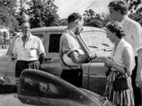 Jack Broadhead, Stirling Moss, and Bob Berry with Mrs. Berry discuss OKV 2 in the foreground.